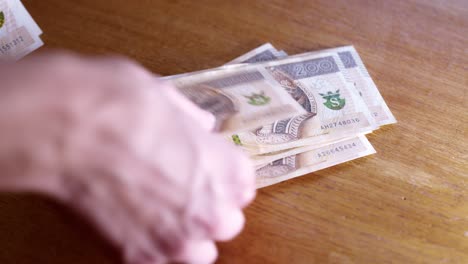 man counts money, cash polish zloty, close-up 200 pln, money on the table