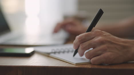 hombre de negocios con pluma escribiendo nuevas citas información en el concepto de organizador raza mixta manos masculinas haciendo notas en papel personal planificador en el escritorio aprender sobre el mercado de valores e inversiones