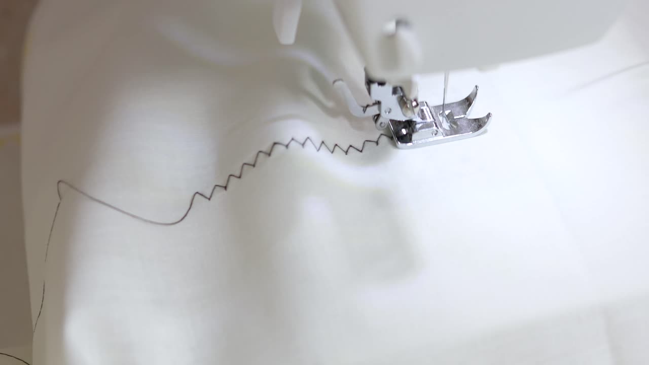 색 직물에 자그 패턴을 바느질 기계로 바느질 한 다음 다른 디자인으로 스티처를 전환했습니다.