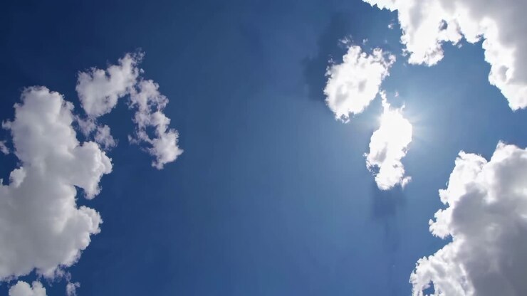 A serene video of a clear blue sky with fluffy clouds, captured from a low-angle perspective