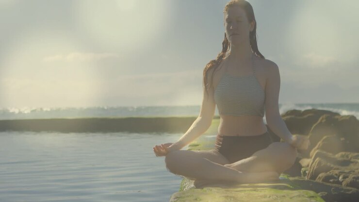 Animación de luces sobre una mujer caucásica practicando yoga en la playa