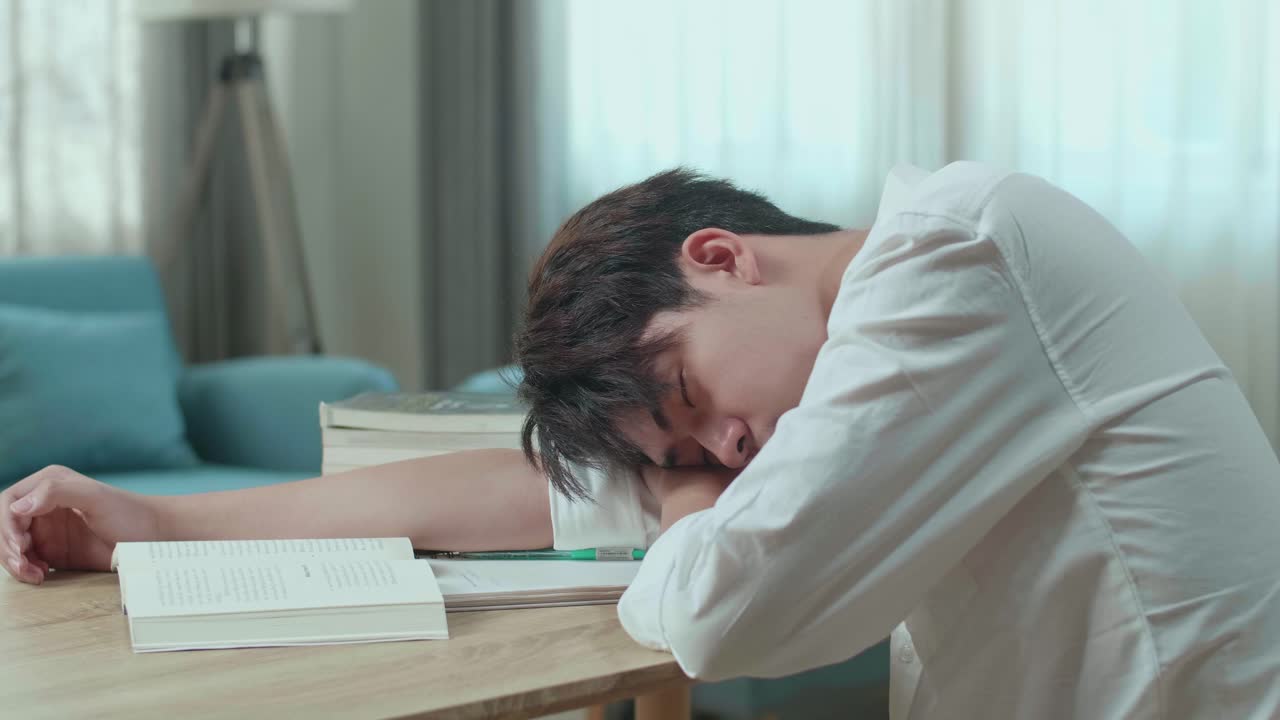 Close Up Of Asian Man Student Sleeping While Reading A Book At Home