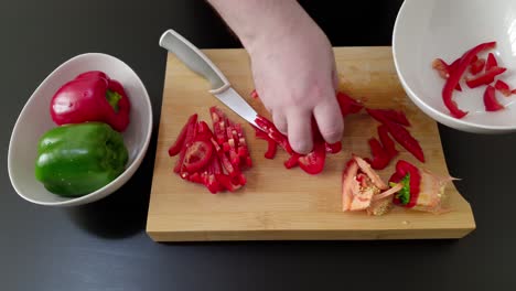 Hand-puts-sliced-red-pepper-in-bowl