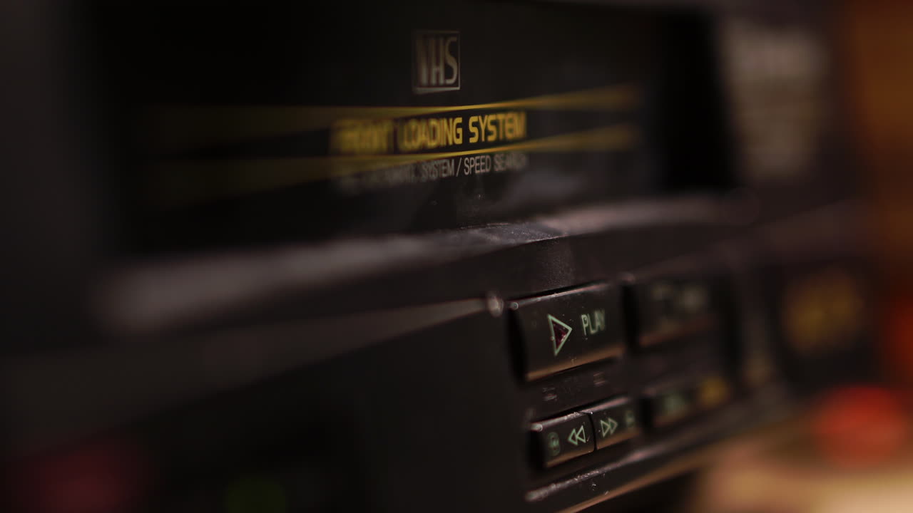 insertando cinta vhs y presionando el botón de reproducción en el reproductor de vcr de la década de 1980