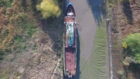 Vista-Aérea-Superior-De-Un-Hermoso-Barco-Abandonado-En-Un-Muelle-Junto-A-Un-Río