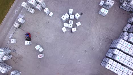 forklift trucks move between large shelves at outside warehouse and load pallets