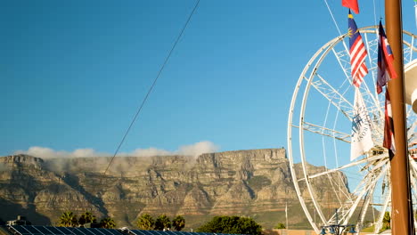 long shot of table mountain from v+a waterfront, big wheel and flags foreground