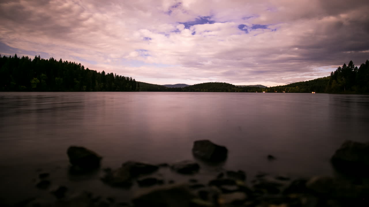 starlapse en un lago tranquilo con nubes en movimiento y luz de la luna