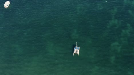 Truck-right-aerial-top-view-shot-of-beautiful-incredible-turquoise-clear-ocean-water-with-small-fishing-boats-near-the-tropical-Bessa-beach-in-the-coastal-capital-city-of-Joao-Pessoa,-Paraiba,-Brazil