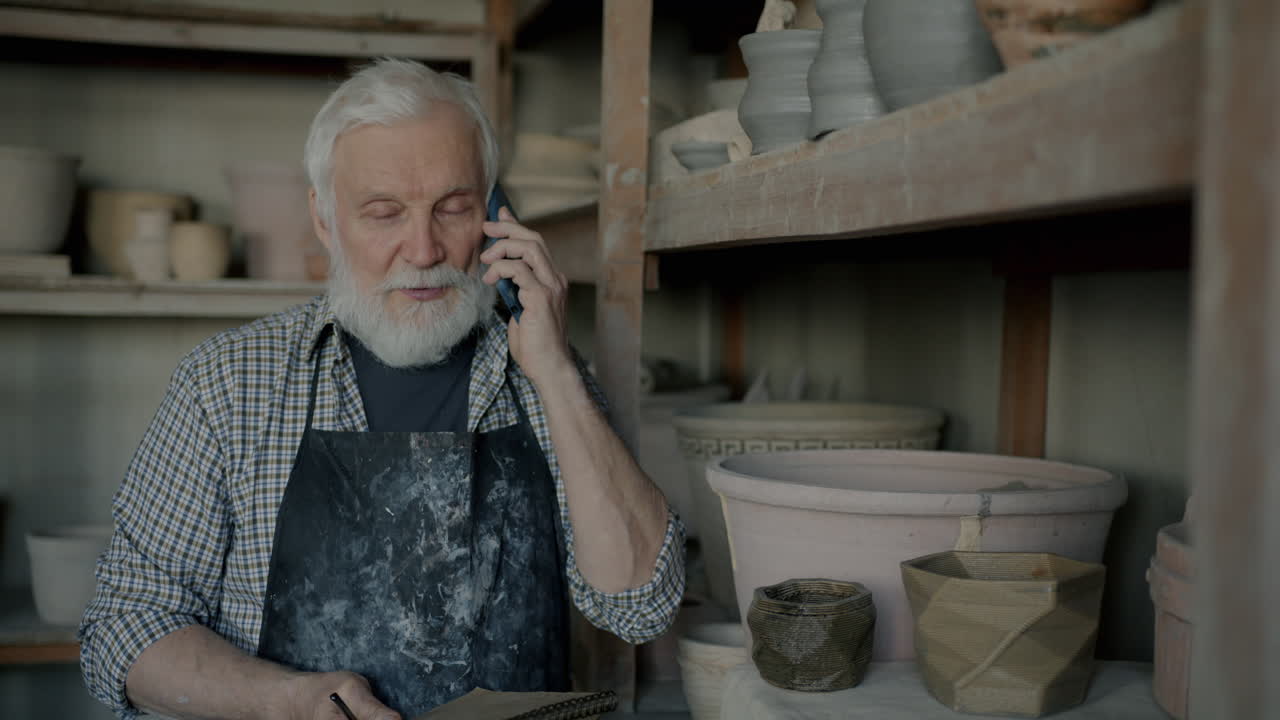Senior Potter on the Phone in His Workshop