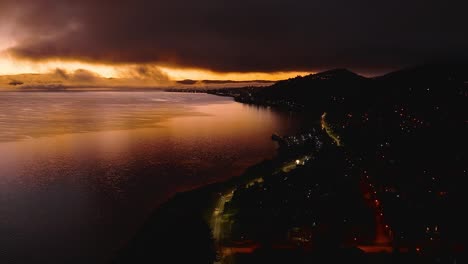 amanecer sobre el lago por la noche con las luces de la ciudad