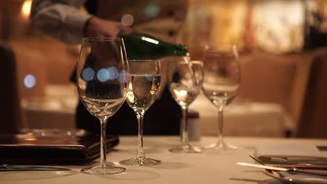 close up shot of waiter pouring water in glass during dinner in restaurant