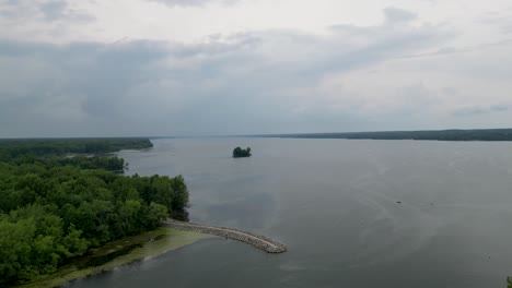 a view of a vast lake with a small island, framed by lush greenery on the shore