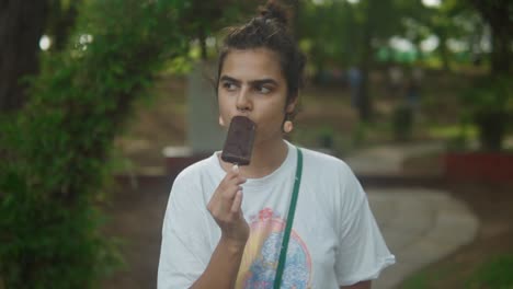 una joven adolescente comiendo helado de chocolate en el parque - el concepto de vacaciones, despreocupación y relajación