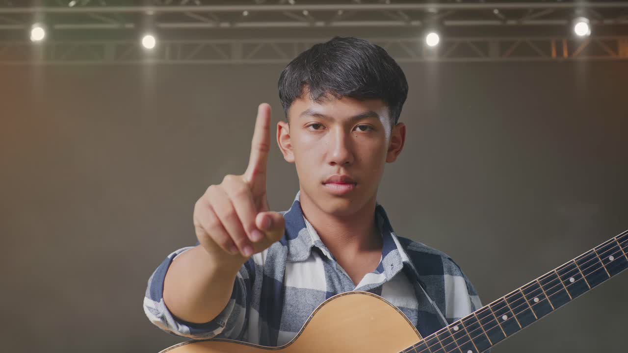 무대 위 에 서 있는 동안 기타 를 연주 하는 아시아 청소년 의 근접 사진
