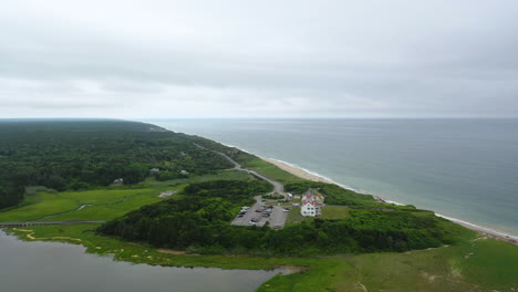 ominous aerial drone footage beach and ocean on dark cloudy day in cape cod, massachusetts with parking lot and marsh