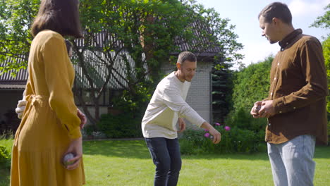 caucasian young man teaching his friends how to throw petanque balls to start the game