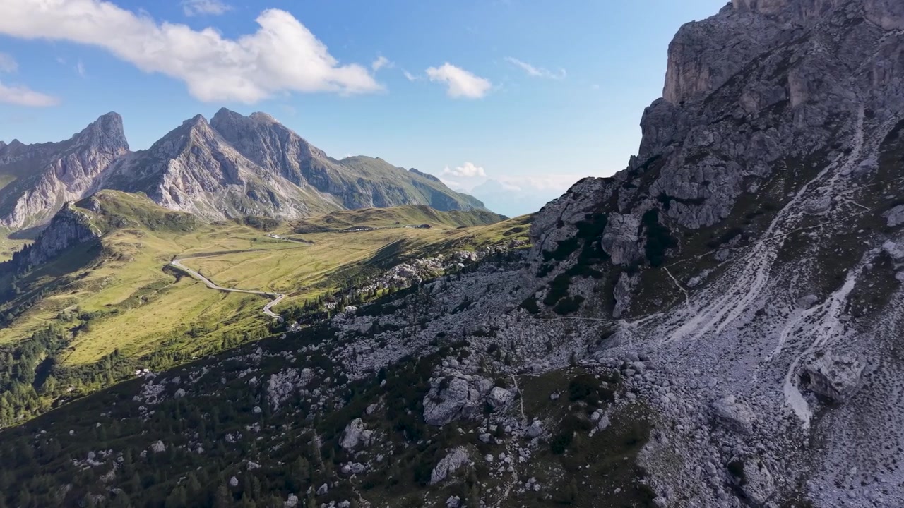 Filmisk droneflyvning langs de barske kalkstensklipper ved Passo Giau, der afslører det alpine landskab og den snoede bjergvej i Dolomitterne, Italien.