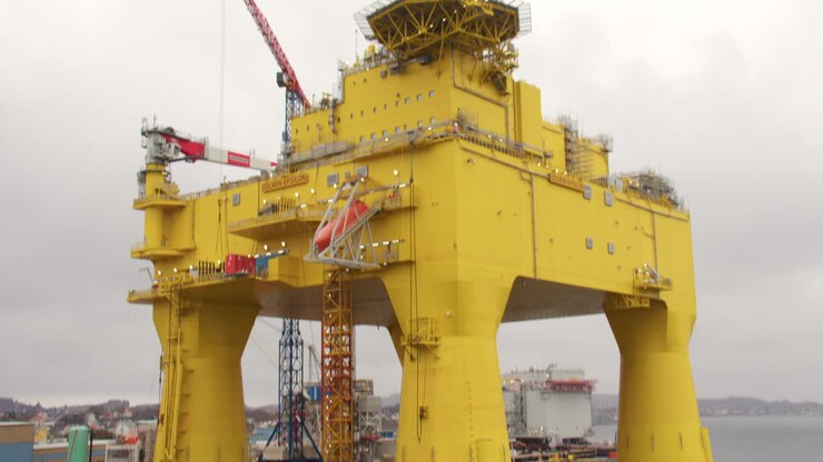 tilting down shot of a oil rig in port having maintenance with crane in background at Haugesund