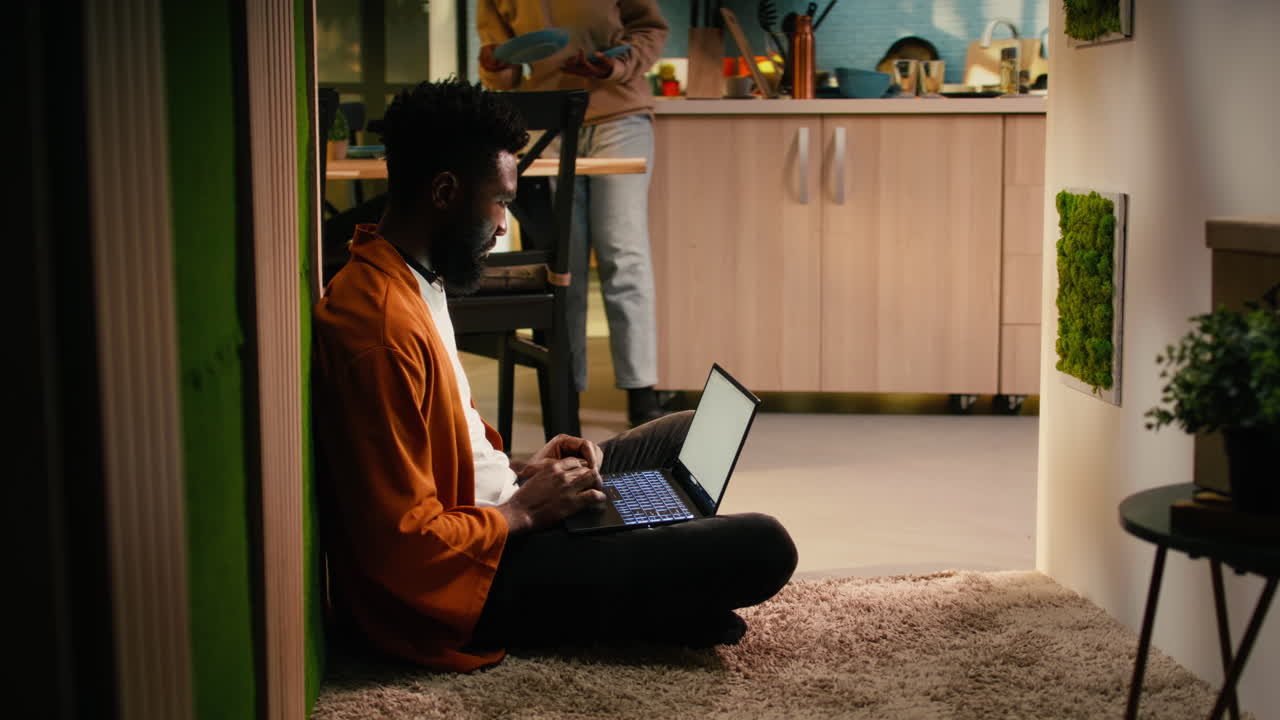 African american person, relaxing with laptop, sitting on the floor at home
