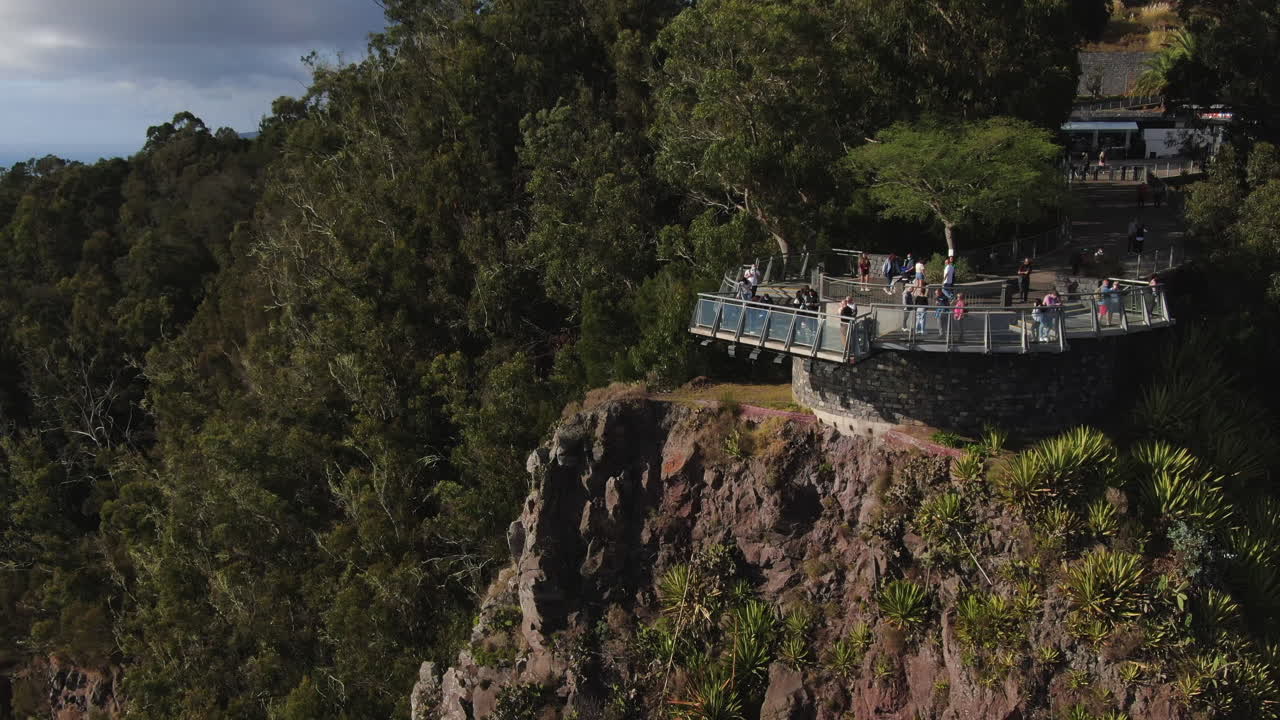 toma aérea cinematográfica y en media órbita al punto de vista de cabo girao y donde se puede ver a los turistas visitando el lugar