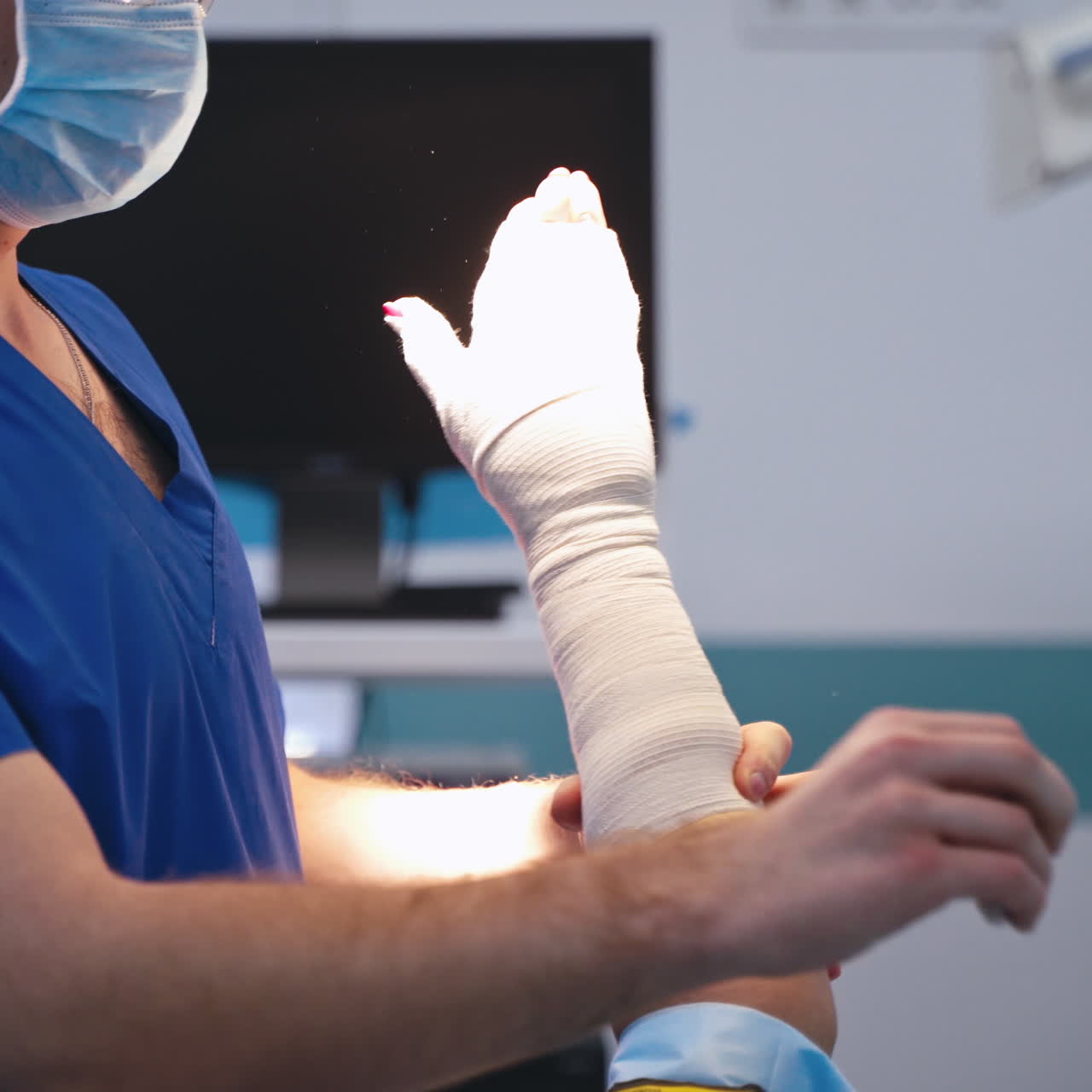 Bandaging arm in clinic. Male doctor puts a tight bandage on the patient's hand. Medical specialist giving emergency help in the hospital. Close-up.