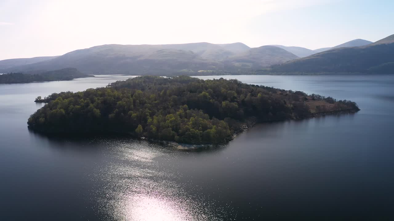 화창한 날 loch lomond의 숲이 우거진 섬 주변을 짧게 청소합니다.