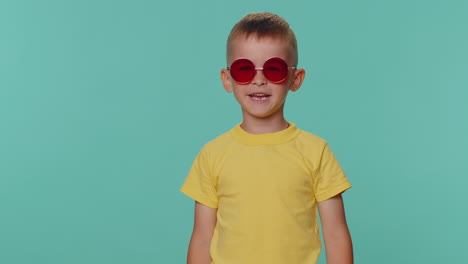 Portrait-of-seductive-little-toddler-children-boy-in-t-shirt-wearing-red-sunglasses,-charming-smile