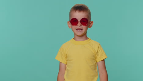 retrato de niños pequeños seductores niño en camiseta con gafas de sol rojas, sonrisa encantadora