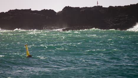 olas rompiendo en las rocas mientras el océano se arremolina debajo