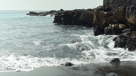 Strong-winds-and-waves-of-water-rushing-towards-the-seashore,-handheld-closeup