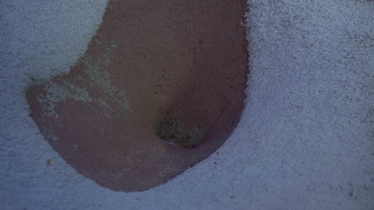 una bola naranja que rueda hacia un obstáculo en un campo de minigolf y finalmente rueda por una tubería hasta otro hoyo