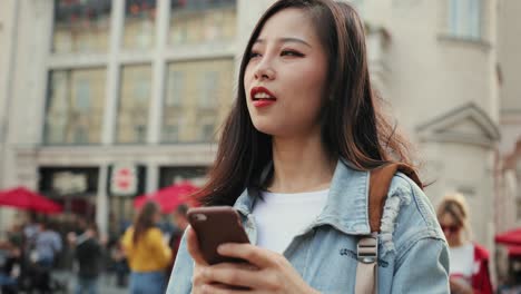 Attractive-Young-Woman-Tapping-And-Scrolling-On-The-Smartphone-While-Chatting-At-The-City-Street