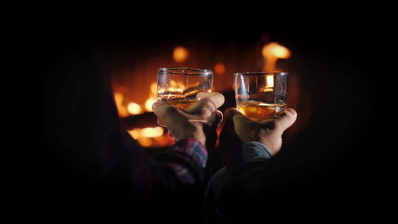 벽난로 남성 휴식의 배경에 위스키 잔을 가진 두 남자의 손