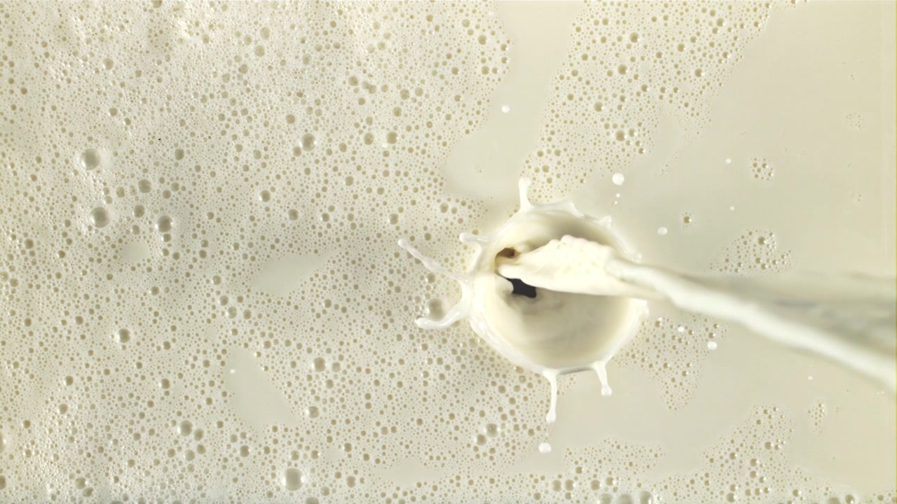 Latte cremoso che si versa su una superficie schiumosa al rallentatore