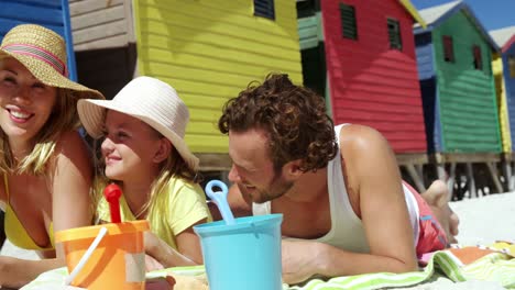 family lying together on blanket at beach