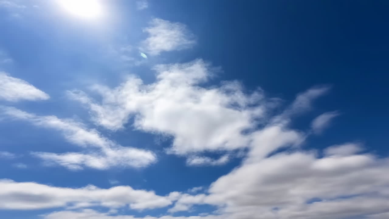 Cielo Azzurro Intenso con Nuvole Bianche e Sole che Attraversa
