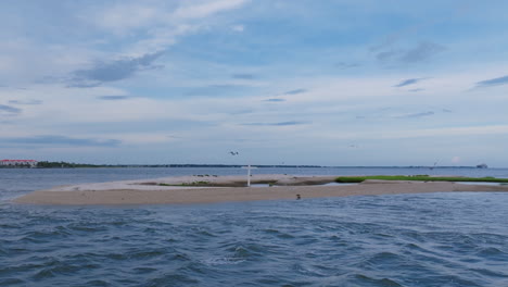 aerial footage of a white cross on a beach that quickly pulls away revealing birds on an island