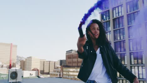 fashionable young woman on urban rooftop using a smoke grenade