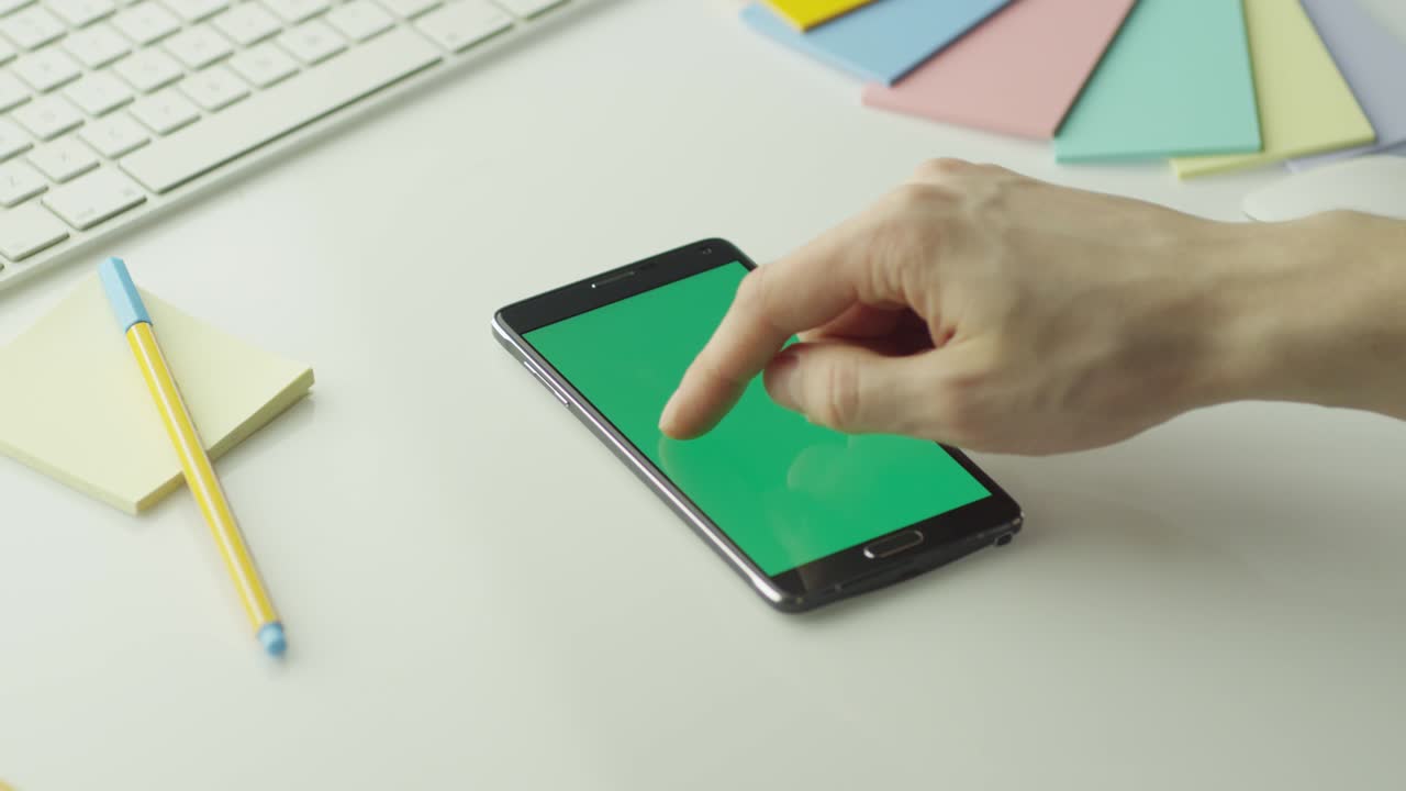 디자이너는 초록색 화면을 가진 안드로이드 드폰을 포트레이트 모드에서 사용하고 있습니다.