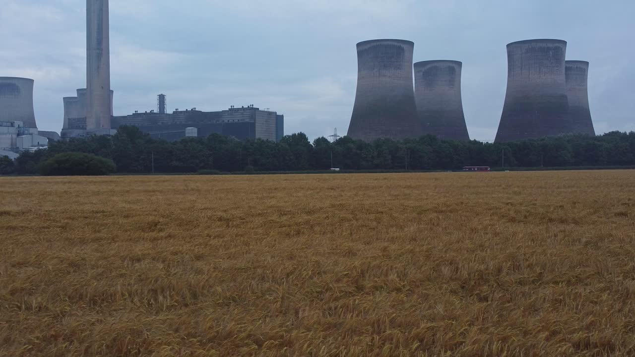 imponente torre de enfriamiento de hormigón estación de energía tierras de cultivo campo vista aérea ángulo bajo retroceder a la izquierda