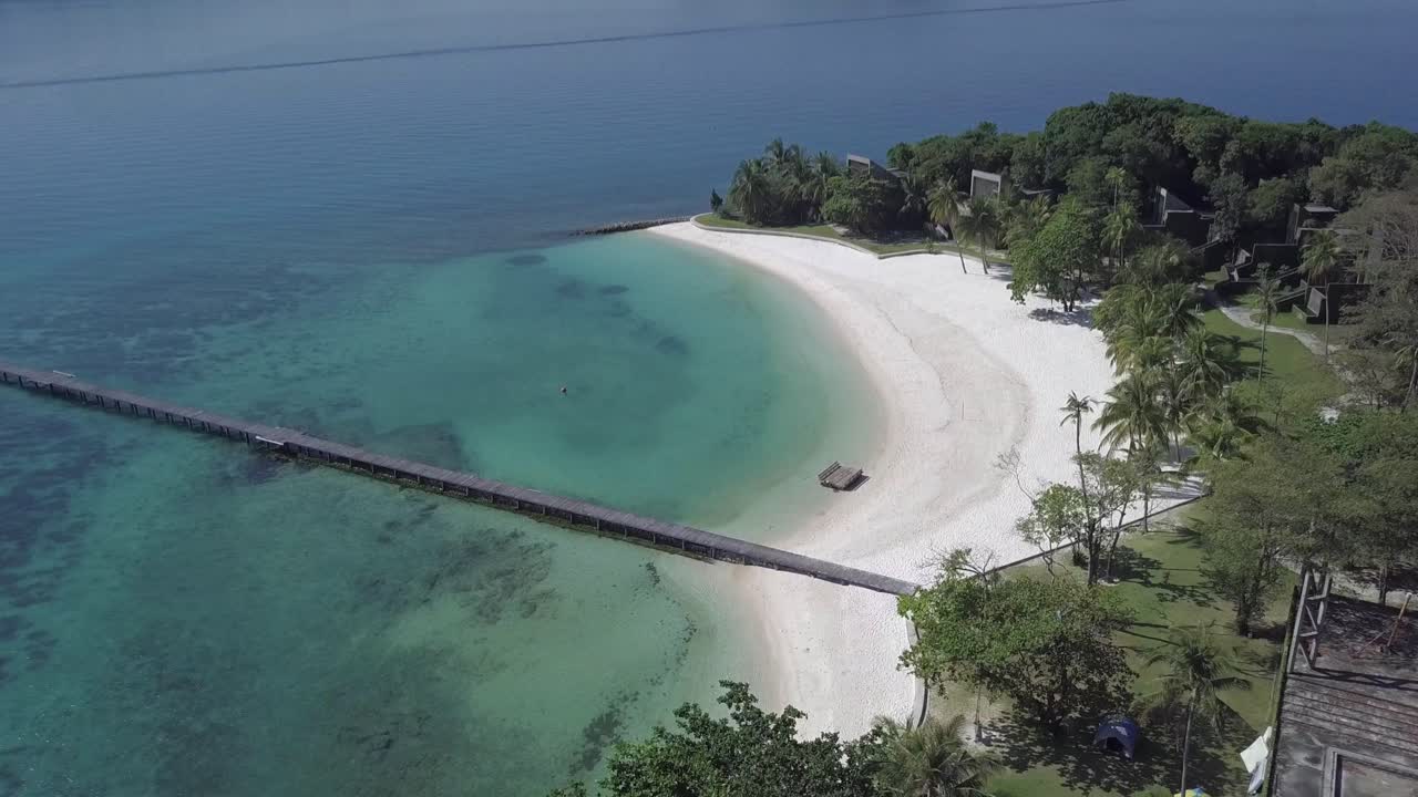 Aerial view of paradise island Koh Kham,Thailand descending slowly from the top of the resort towards the pier and white sand beach.