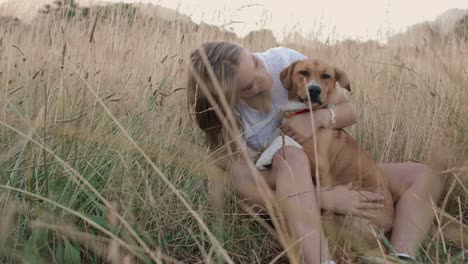 young woman sitting in long grass with her dog