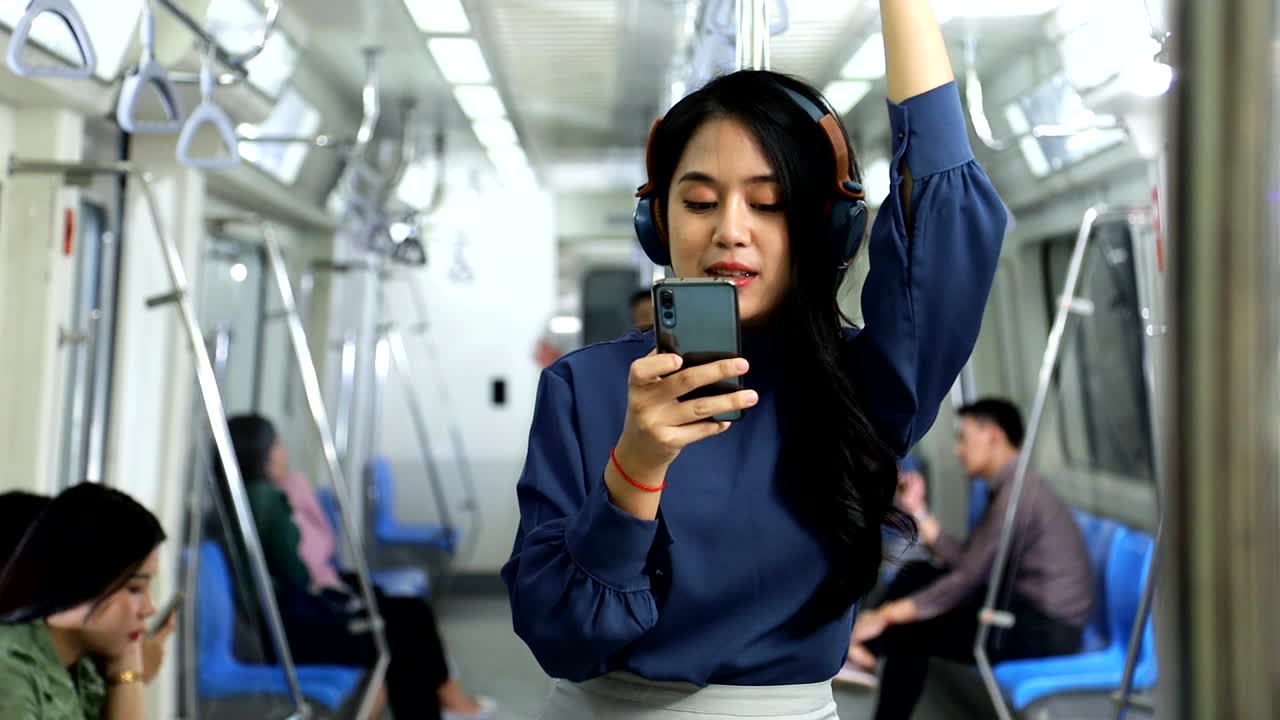 estilo de vida de una joven asiática que usa un teléfono móvil con auriculares mientras toma el tren del metro para ir a trabajar en la hora pico de la mañana
