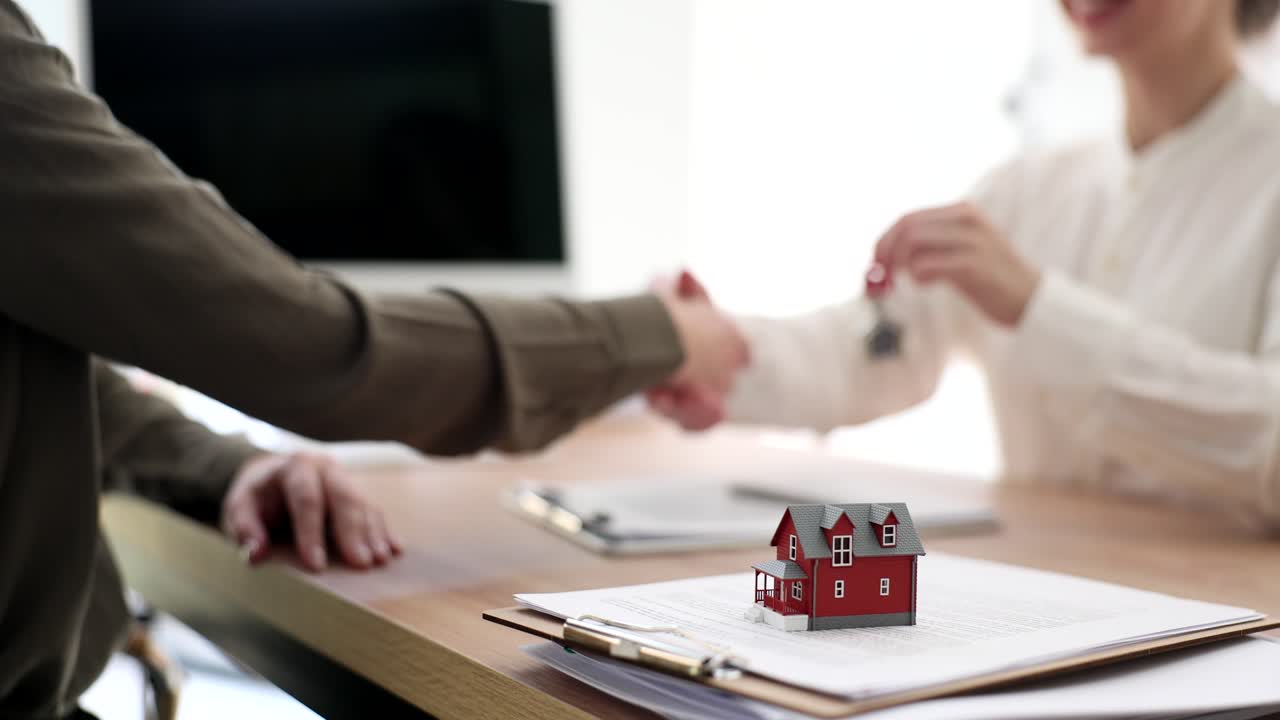 Un agente immobiliare consegna le chiavi di un cottage a una cliente.