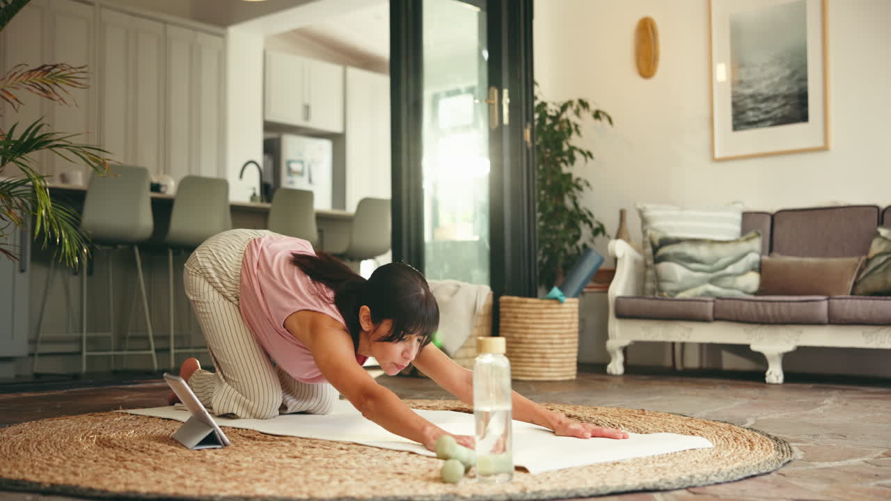 Kvinne som praktiserer yoga på matte i stuen sin