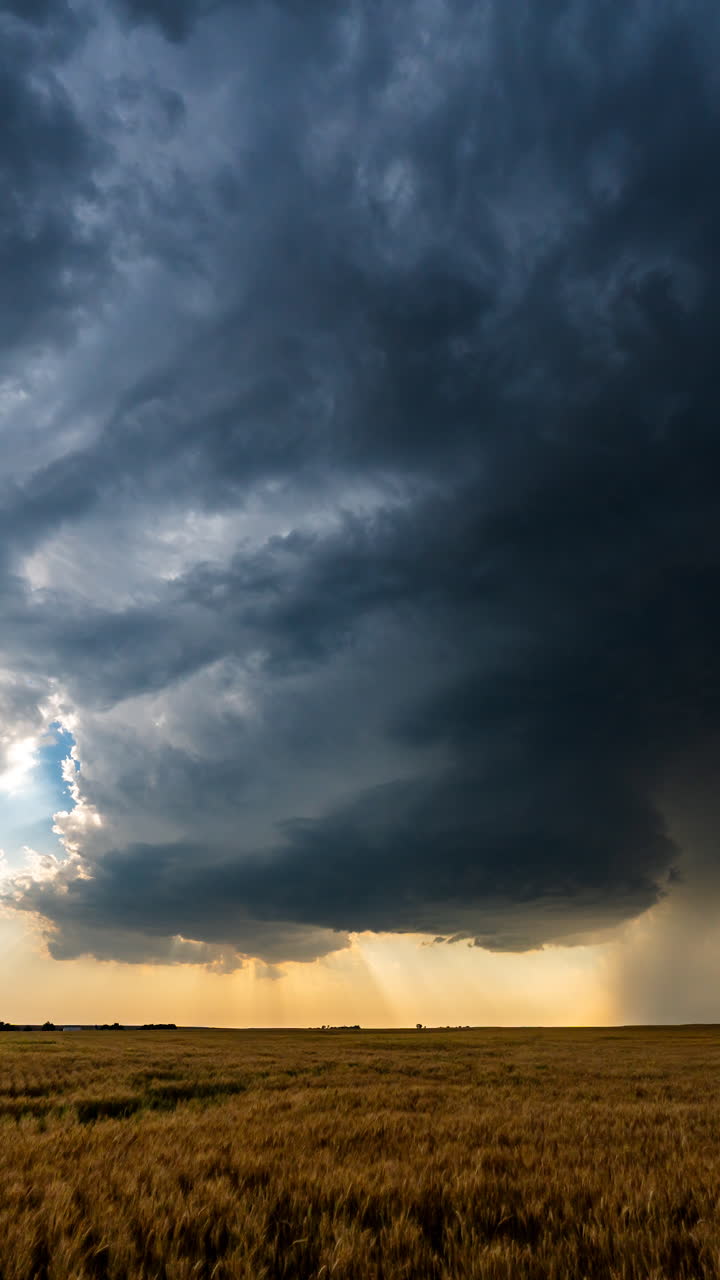 Stormskyer danner en dramatisk himmel over et åbent landskab med vind, regn og en tekstureret skymasse-atmosfære