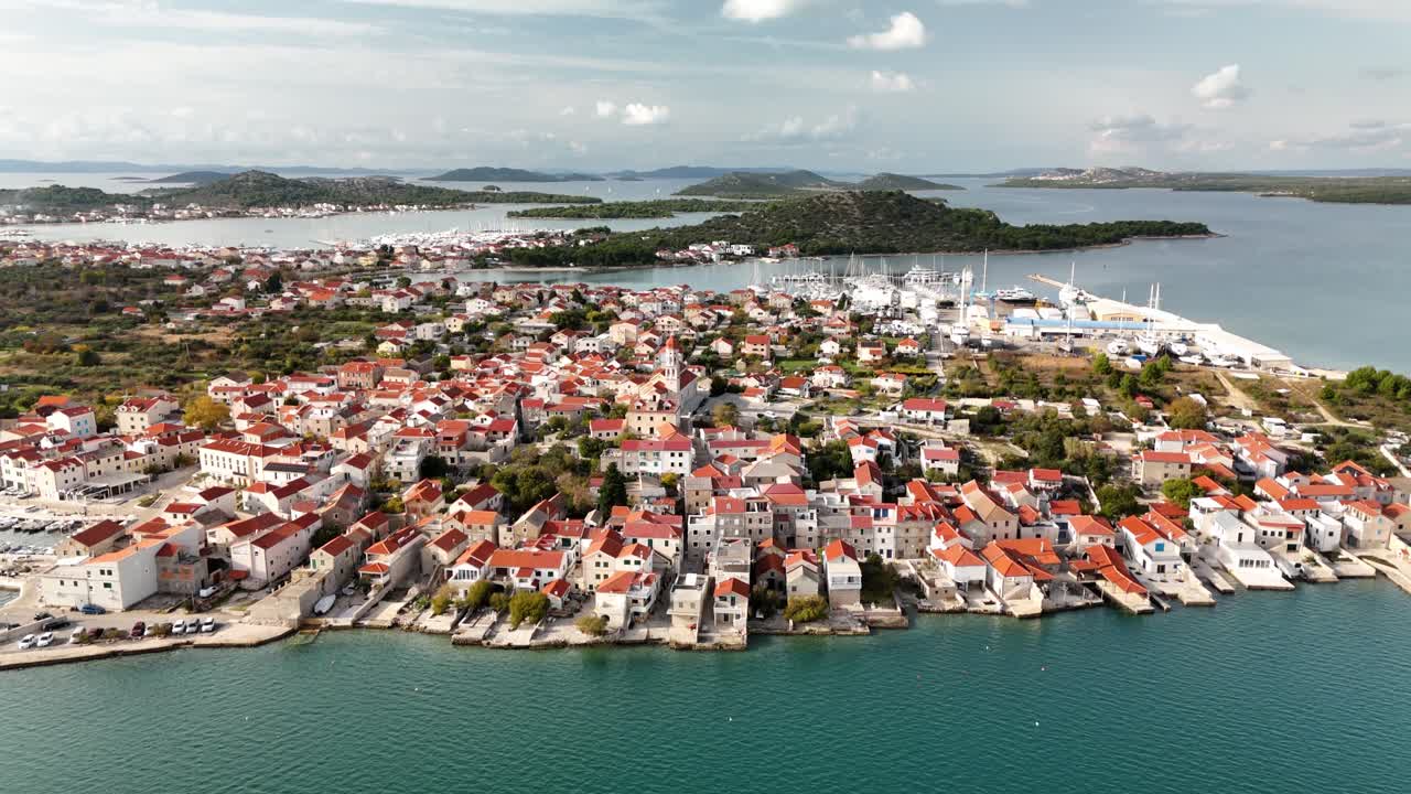 Drone ascends over Betina, gradually revealing the old town, historic rooftops, and the marina behind it on the island of Murter, Croatia