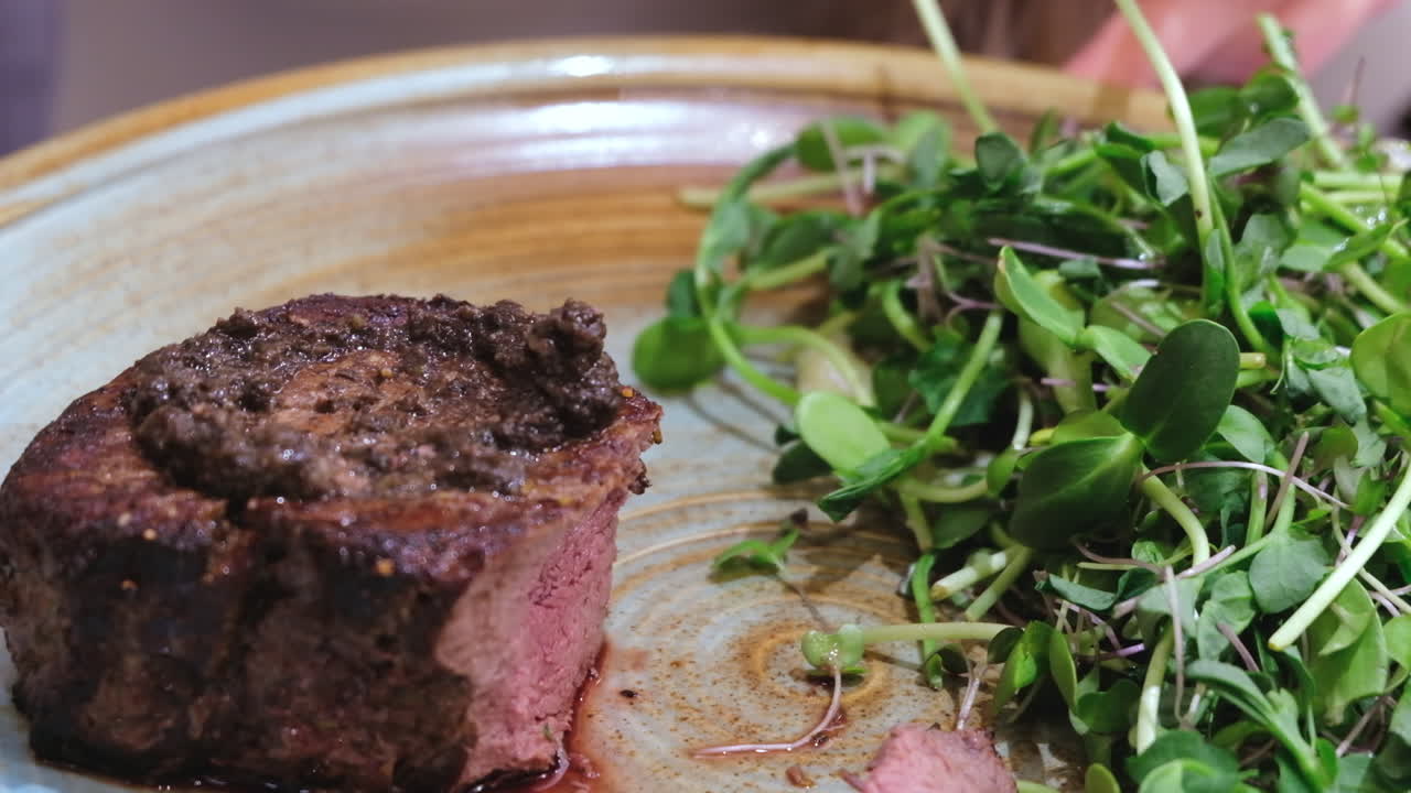 Close up of a woman cutting a piece of filet mignon at a restaurant