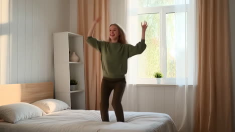 young woman happily jumping on bed in bedroom